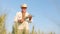 A farmer in an Embroidered Shirt and hat stands in the middle of a field and holds ears of wheat