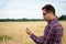 A farmer examines a plant in a wheat field, his hand he holds a glass test tube with the test substance. Smart farming using