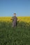 Farmer examining blossoming rapeseed and wheat field and gesturing