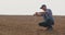 Farmer examining soil quality while crouching at farm