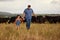 Farmer father, child or family with cows on a farm, grass field or countryside. Sustainability or environmental dad and