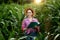 Farmer with a folder stands in a corn field and checks the growth of vegetables. Agriculture - food production, harvest concept