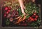 Farmer folding fresh vegetables in wooden box on dark background. Woman hands holding freshly bunch harvest. Healthy organic food