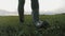 Farmer goes with rubber boots along green field. Rubber boots for work use. A worker go with his rubber boots at sunset