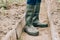 Farmer in green rubber boots  legs in a close-up.