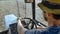 Farmer in hat, sits inside in the tractor cabin, rides on the field with plow.