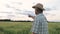 A Farmer In A Hat Stands In A Field Pointing At The Object With His Finger