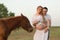 A farmer with his pregnant wife at sunset on his farm. Posing with a horse