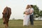 A farmer with his pregnant wife at sunset on his farm. Posing with a horse
