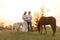 A farmer with his pregnant wife at sunset on his farm. Posing with their pets