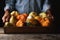 Farmer at his stand holding a wood crate of Autumn vegetables and decorative gourds and pumpkins, with warm side light