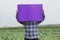 Farmer hold blank violet paper poster at garden background