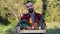 Farmer holding wooden Box full of Vegetables on the organic farm. Portrait of smiling caucasian bearded man in the garden.