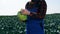 Farmer holds cabbage while standing on a plantation.