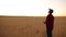 Farmer holds remote controller with his hands while quadcopter is flying on background. Drone ascends behind the