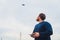 Farmer holds remote controller with his hands while quadcopter is flying on background. Drone hovers behind the