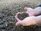 A farmer inspects the field before sowing seeds, lumps of soil in his hands
