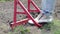 A farmer in jeans digs the ground with a red fork-shaped shovel. A miracle shovel, a handy tool