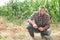 Farmer kneeling by crops