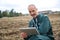 Farmer kneeling in field using a digital tablet