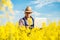 Farmer with laptop in the blooming rapeseed field