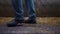 Farmer legs walking cowshed on straw closeup. Worker feet going near stalls.