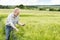 Farmer Looks on Tablet Screen While Holding Wheat Plant