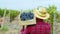 Farmer man in the middle of vineyard walking through the vineyard and holding the wooden basket full of black grapes