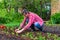 Farmer man transplanting tomato seedlings into open ground against green garden and country house. Spring work in kitchen-garden,