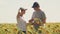 Farmer man and woman with laptop shake hands on a blooming sunflower field. agribusiness concept. businessman and