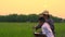 Farmer mother and daughter looking rice field and checking data in laptop on sunset