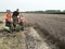 Farmer on old tractor mows wheat with plow behind