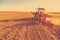 Farmer plowing stubble field with red tractor