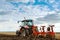 Farmer plowing stubble field with red tractor.