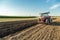 Farmer plowing stubble field with red tractor.