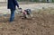 A farmer plows the land with a hand-held motor plow. Agricultural machinery: cultivator for tillage in the garden, motorized hand