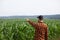 Farmer points to a green field of corn. Agricultural industry