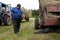 Farmer repairing tractor in field, during hay.