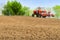 Farmer repairing tractor with seeder in field