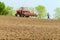 Farmer repairing tractor with seeder in field