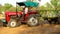 Farmer riding tractor in the field also towing trolley loaded with organic fertilizer. High quality footage