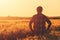 Farmer in ripe wheat field planning harvest activity