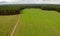 Farmer's grren field with hay rolls. Road countryside. Forest. Aerial drone view
