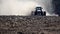 Farmer`s powerful tractor plowing the dry and arid ground with a huge cloud of dust