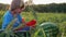 Farmer`s son eating watermelon with pleasure on the field of organic farm.