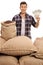 Farmer with sacks filled with coffee beans holding money bundles