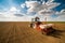 Farmer seeding, sowing crops at field.