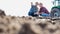 Farmer showing field while examining soil with senior farmer at farm against tractor