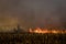 Farmer silhouette fighting fire in agricultural farming field with wall of smoke