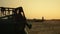 Farmer silhouette at wheat field harvesting equipment at golden sunset time.